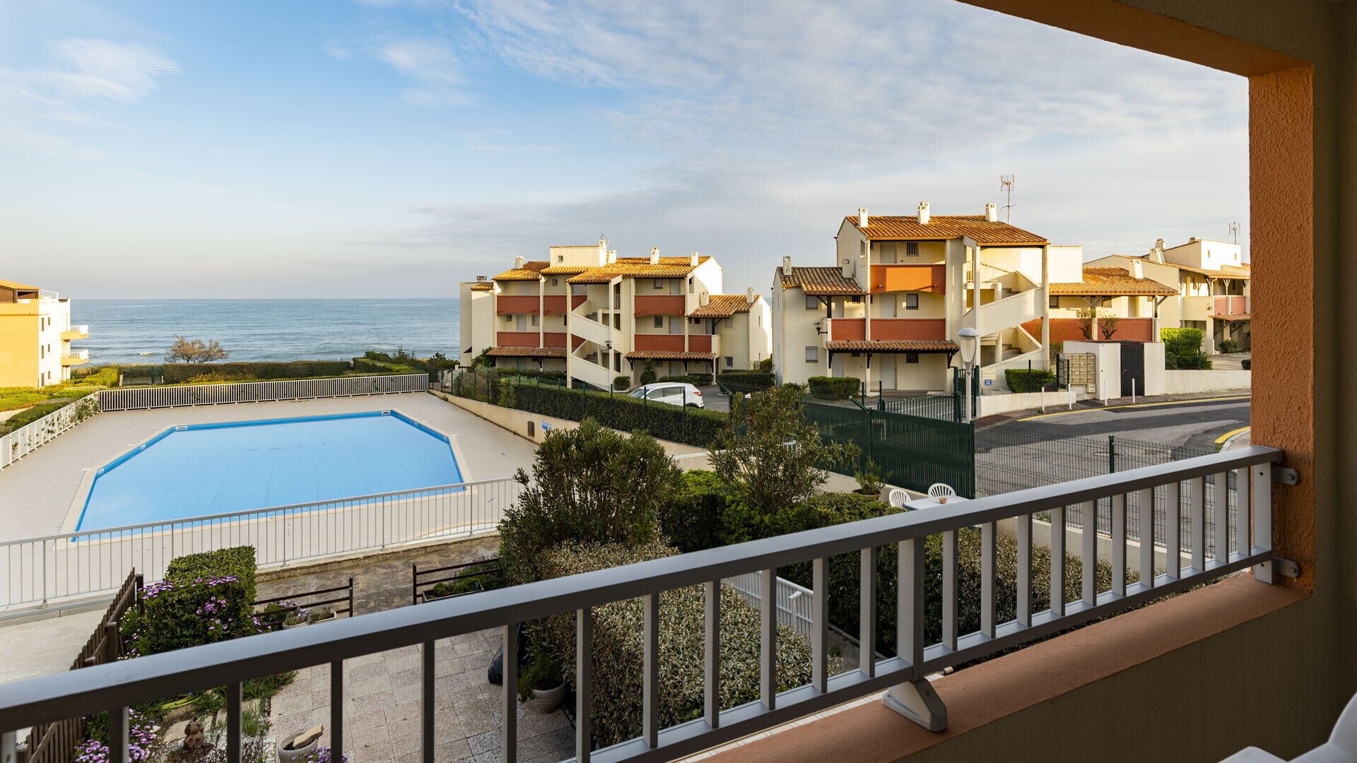 Edifício residencial com piscina, vista para o mar e varanda com guarda-corpo.