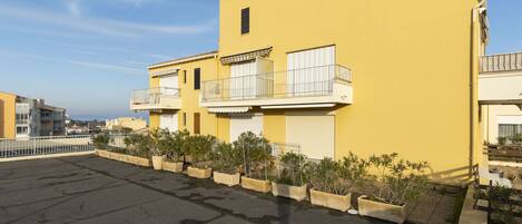 Un edificio giallo con balconi e piante in vaso.