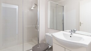 A modern bathroom with a glass shower enclosure, a white sink, and a large mirror.
