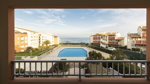 Une vue sur une piscine, avec un ciel dégagé et l’océan en arrière-plan.