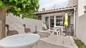 Un patio con una mesa redonda y sillas, una bicicleta y esculturas decorativas de pájaros.