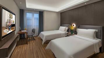 A hotel room with two beds, a desk, a chair, a TV, and a window with curtains.