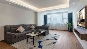 Una sala moderna con un sofá modular, una mesa de centro y un ventanal con cortinas.