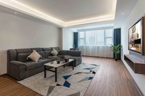 A modern living room with a sectional sofa, a coffee table, and a large window with curtains. - Citadines Zhengda Mall Hefei (Hefei)