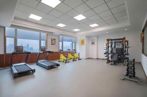 Un'ampia palestra con tapis roulant, cyclette e attrezzature per l'allenamento con i pesi.