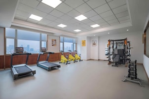 Un gimnasio amplio con cintas de correr, bicicletas estáticas y equipo de levantamiento de pesas.