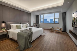 A modern hotel room with a large bed, a desk, a chair, a TV, and a city view. - Citadines Zhengda Mall Hefei (Hefei)