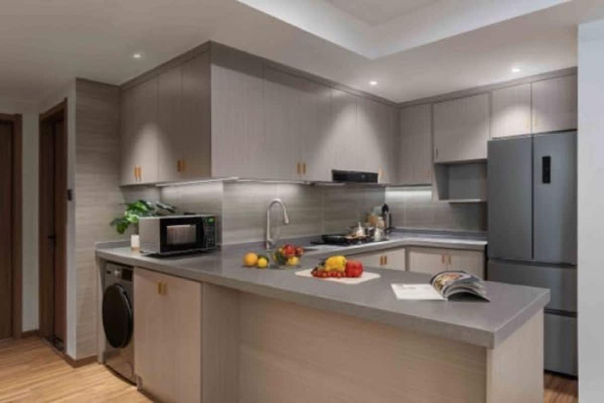 A modern kitchen with grey cabinets, a built-in microwave, a sink, and a refrigerator.