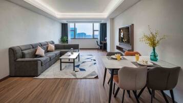A modern living room with a sectional sofa, a coffee table, and a dining area with chairs.