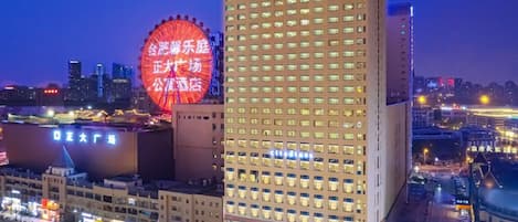A high-rise hotel with a modern design, featuring a prominent circular structure in the background.