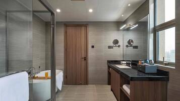 A modern bathroom with a glass-enclosed shower, a freestanding bathtub, a vanity with a black countertop, and a large mirror.
