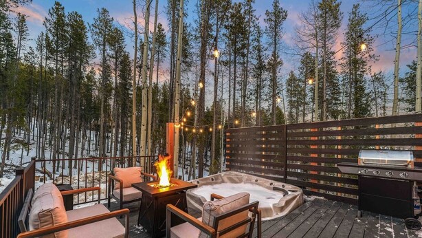 An outdoor deck with a hot tub, a grill, and string lights. - *NEW* Hidden Ruby A-Frame (Evergreen)