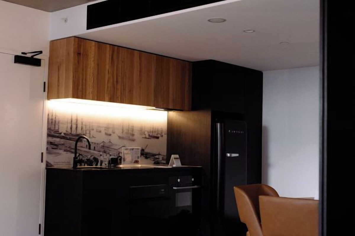 A compact kitchen with a wooden cabinet, a built-in sink, and a refrigerator.