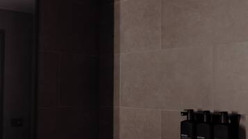 Un baño moderno con azulejos oscuros, un lavabo negro y un espejo.