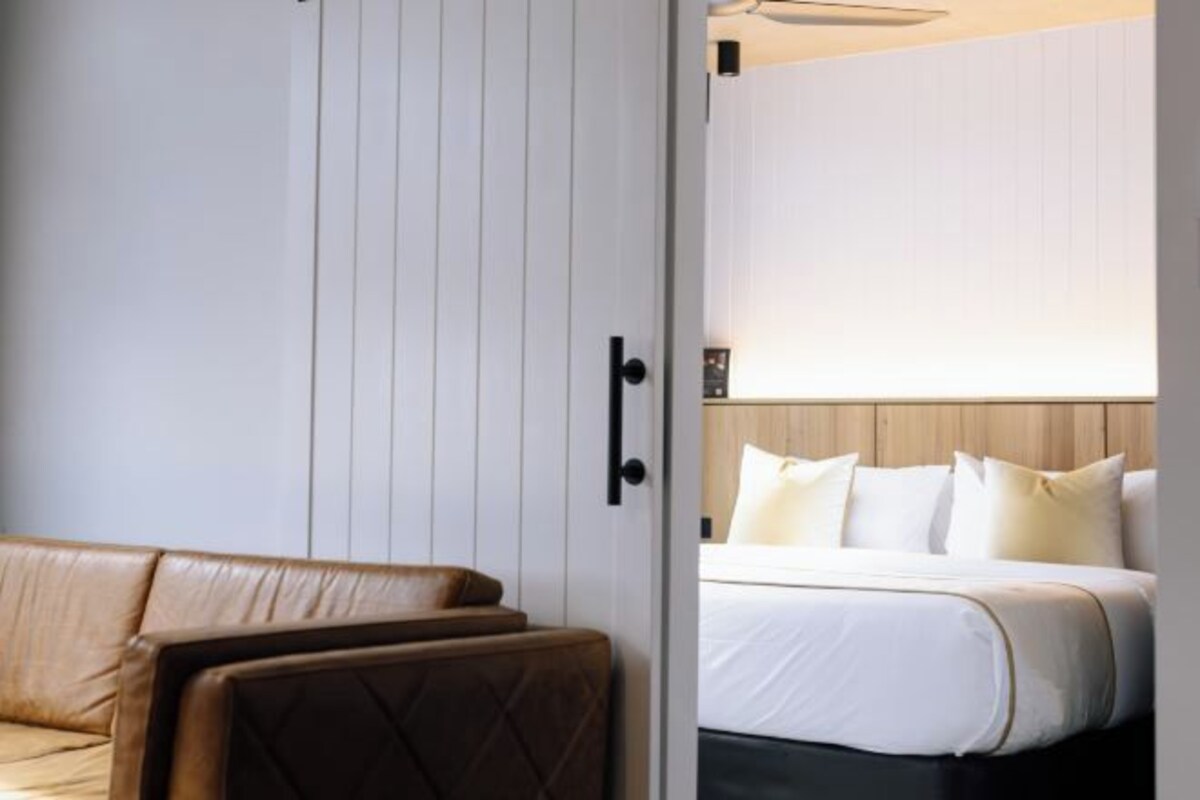 A hotel room with a bed, a sofa, and a wardrobe.