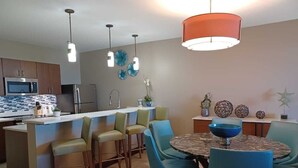 Une cuisine moderne dotée d’un îlot central, de tabourets de bar et d’une table à manger avec des chaises.