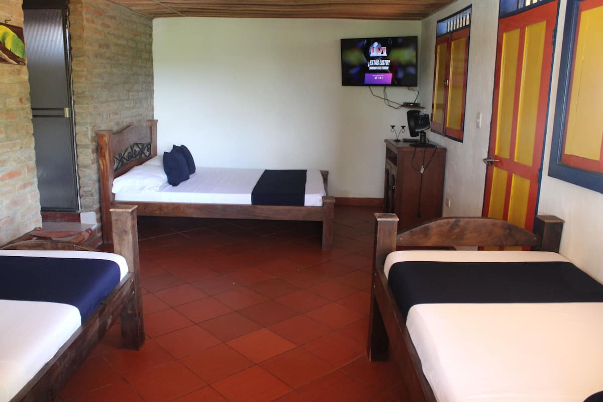 A room with two beds, a television, and a wooden cabinet.