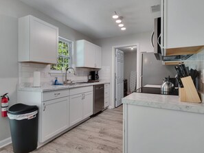 A modern kitchen with white cabinets, a stainless steel sink, and a coffee maker.
