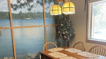 Un coin repas avec une grande table, des chaises en bois et un sapin de Noël.