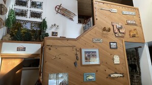 Interieur van een blokhut met houten wanden, een kruisboog, vissenborden en een bord met de tekst welkom.