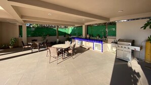 An outdoor patio with a grill, seating area, and a tiled floor. - Condos Clauss (Mazatlán)