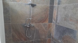 A shower area with a handheld showerhead and a wall-mounted faucet. - Tropical Studio (Collectivité de Saint-Martin)