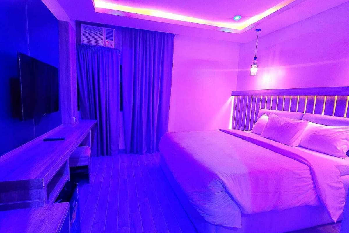 A modern bedroom with a bed, a TV, and a desk.