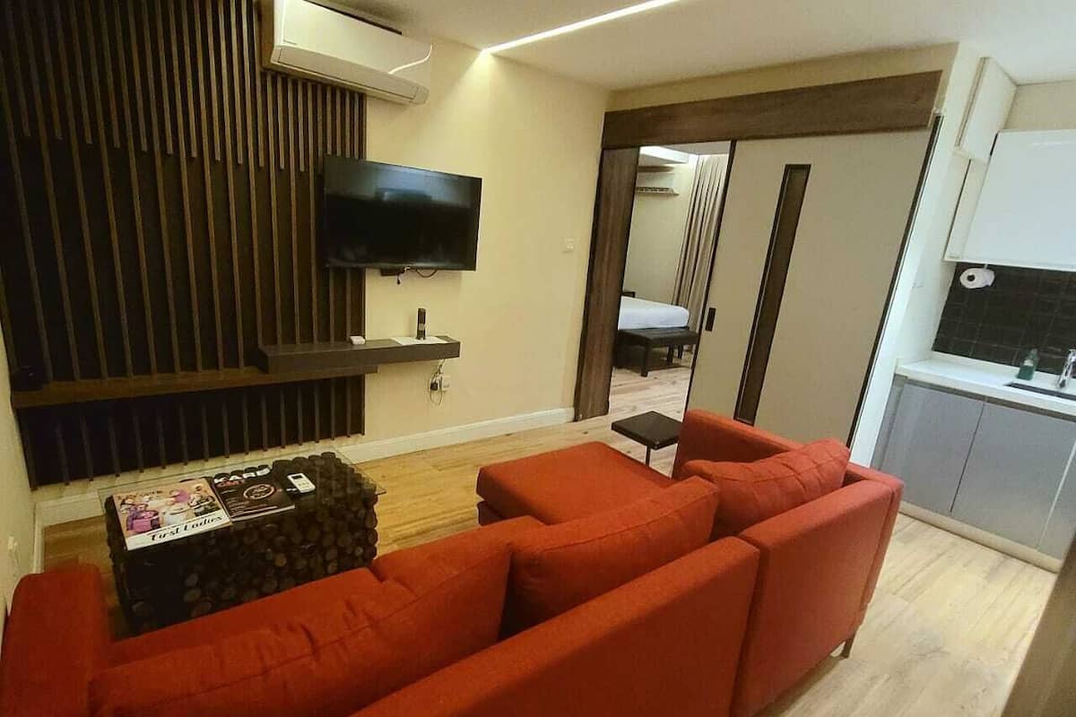 A modern living room with a red sofa, a flat-screen TV mounted on the wall, and a small table with magazines.