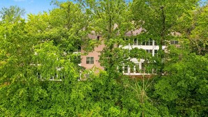 Un edificio de varios pisos con fachada de ladrillo, rodeado de abundante follaje verde.