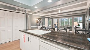 Una cocina con gabinetes blancos, encimeras de granito y ventana con vista a un patio.
