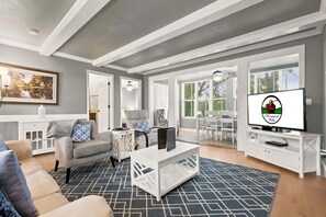A living room with a sofa, coffee table, TV, and a painting on the wall.