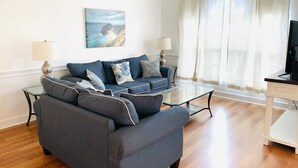 Un salon comprenant un canapé, une table basse en verre et un tableau accroché au mur.