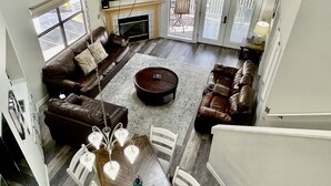 A spacious living area with a fireplace, leather sofas, a dining table with chairs, and a staircase. - Lissa's Retreat- 4 BDRM 3 BA Sleeps 12! Indoor Pool, Gym, Fishing, Golf, & Park (Branson)