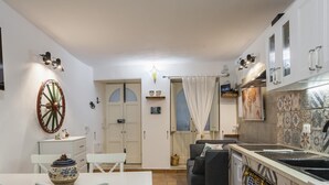 A compact kitchen with white cabinets, a dining table, and a small seating area. - La Casa di Rosa by Wonderful Italy (Syracuse)
