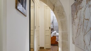 A hallway with a tiled floor, a door leading to a room with a bed, and a marble-patterned wall. - La Casa di Rosa by Wonderful Italy (Syracuse)