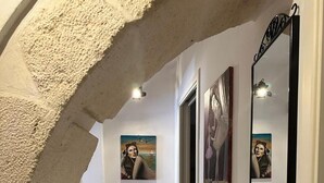 A hallway with a stone archway, tiled floor, and wall-mounted artwork. - La Casa di Rosa by Wonderful Italy (Syracuse)
