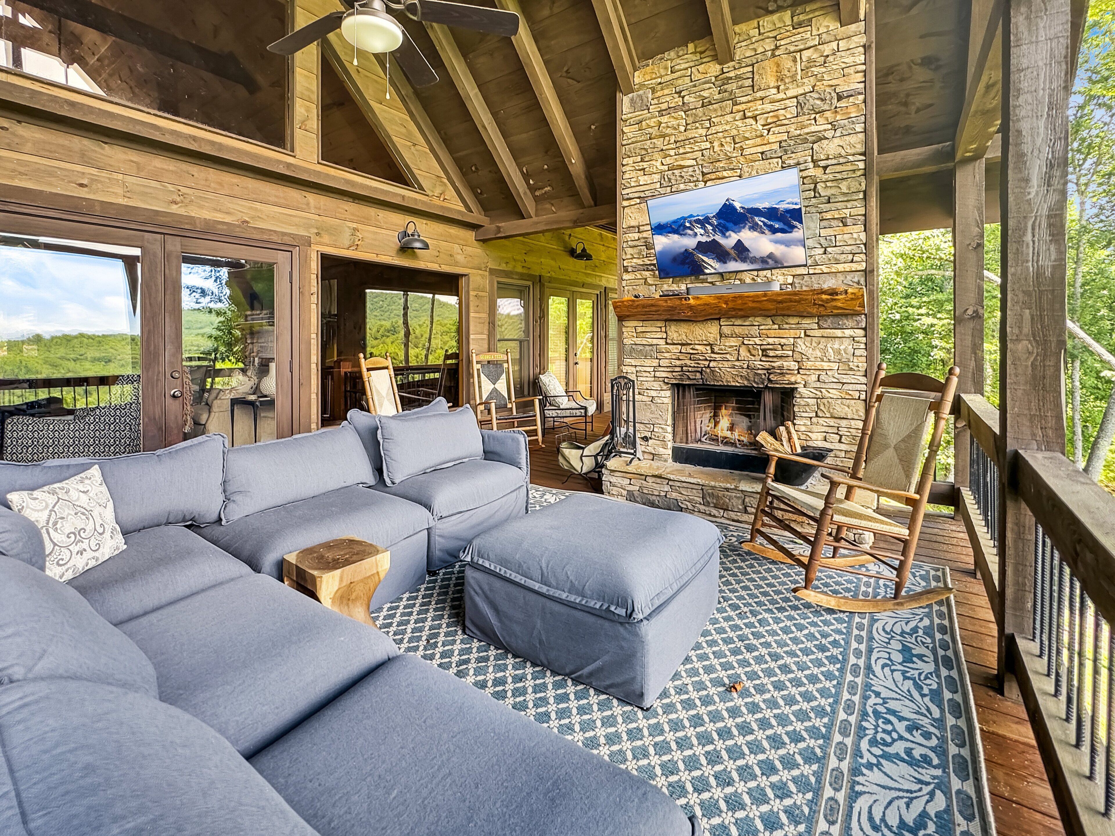 A cozy living area with a stone fireplace, a large sectional sofa, and a television mounted on the wall.