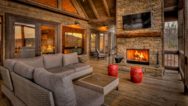 A cozy living room with a stone fireplace, comfortable seating, and a large TV mounted on the wall. - The Silver Fox - Modern Chic Decor | Hot Tub | Aska Adventure Area (Blue Ridge)