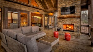 A cozy living room with a stone fireplace, comfortable seating, and a large TV mounted on the wall. - The Silver Fox - Modern Chic Decor | Hot Tub | Aska Adventure Area (Blue Ridge)