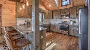 A kitchen with wooden cabinets, a marble countertop, a stainless steel refrigerator, and a built-in oven. - The Silver Fox - Modern Chic Decor | Hot Tub | Aska Adventure Area (Blue Ridge)