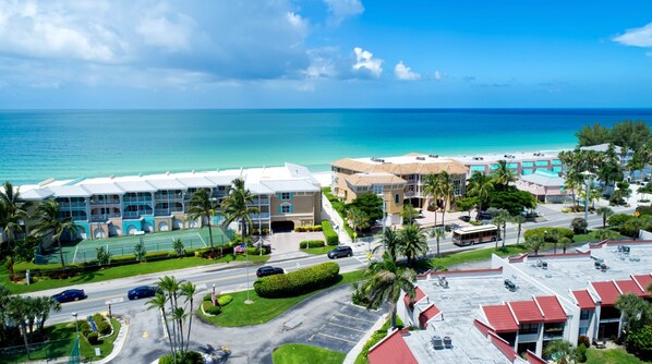 A coastal hotel with multiple buildings, a tennis court, and a parking lot.