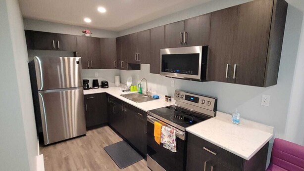 A modern kitchen with dark cabinets, stainless steel appliances, a microwave, and a gas stove.