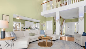 Un salon spacieux avec un canapé d’angle, une table basse et un escalier menant à un niveau supérieur.