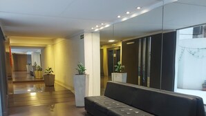 A modern lobby with a black leather sofa, potted plants, and a glass partition. - What you were looking for in Nueva Cordoba (Córdoba)