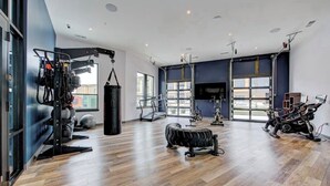 A spacious gym with various exercise equipment, large windows, and a modern design.