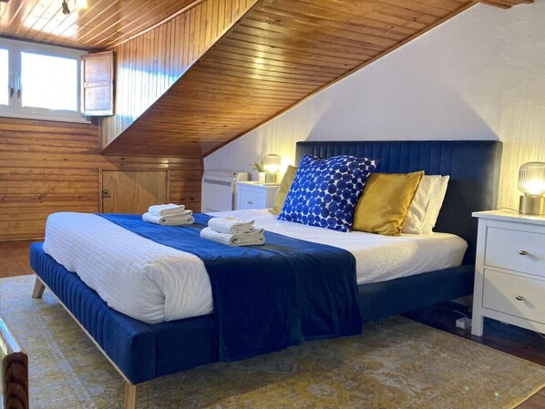 A bedroom with a large bed, a nightstand, and a window.