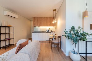 Ein kompakter Wohnraum mit Küchenzeile, Essbereich und einer Sitzecke mit Sofa und Sesseln.