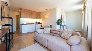 A modern living room with a sofa, a dining table, a kitchen area, and a plant. - Bright Apartment Next to D. Luis Bridge by Lisbeyond (Vila Nova de Gaia)