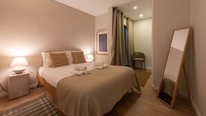 A hotel room with a bed, bedside lamps, a chair, a mirror, and a painting on the wall. - Cozy Apartment only 500m from Douro River | With A/C by Lisbeyond (Vila Nova de Gaia)