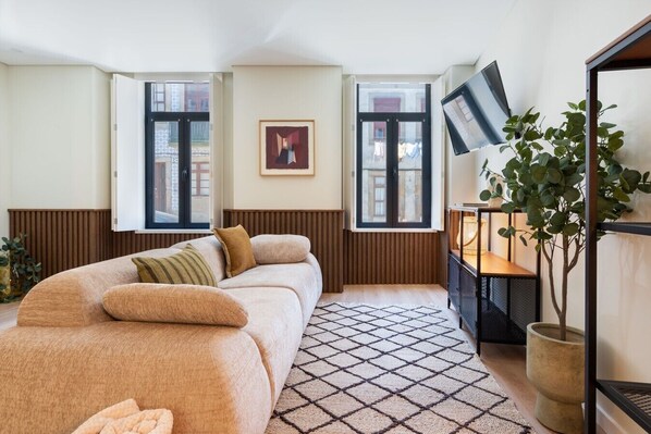 A modern room with a sofa, a small table, a plant, and a painting on the wall.